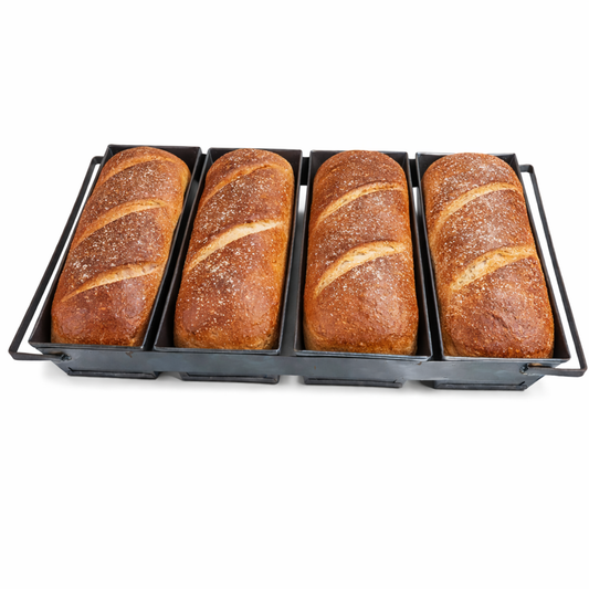 Four freshly baked artisan bread loaves with golden crusts inside a commercial 4-strap black steel baking pan.