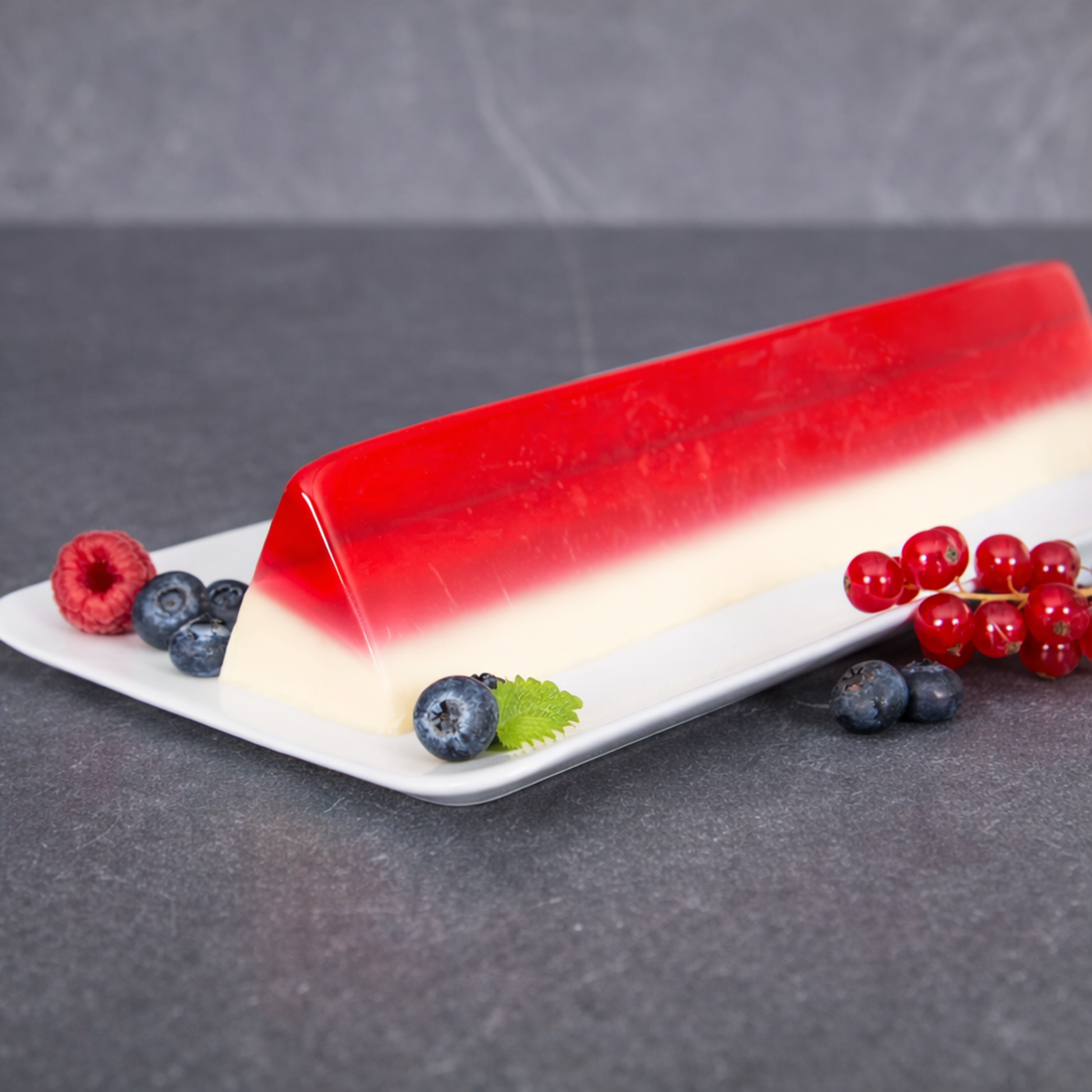 Triangular layered dessert mousse and jelly made in professional stainless steel V-shape mold, plated with fresh berries for catering