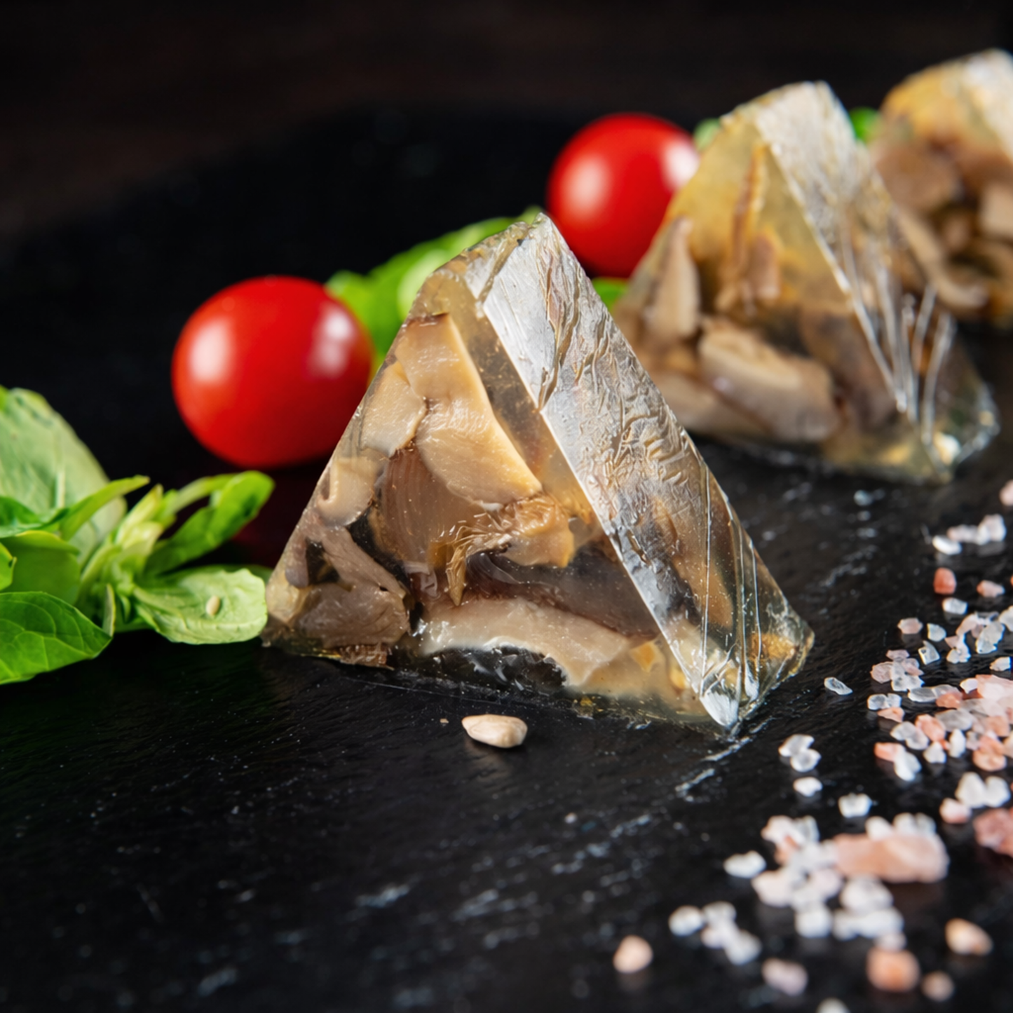 Gourmet triangular mushroom aspic slices (vegetable terrine) made in V-shape stainless steel mold, plated with herbs for professional catering appetizers.