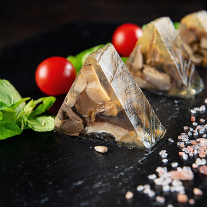 Gourmet triangular mushroom aspic slices (vegetable terrine) made in V-shape stainless steel mold, plated with herbs for professional catering appetizers.