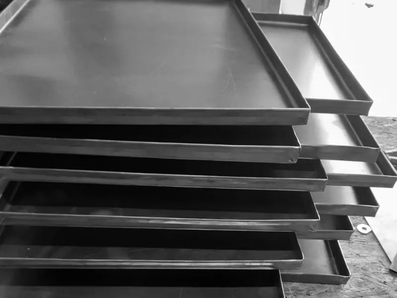 Professional black steel baking trays in factory workshop