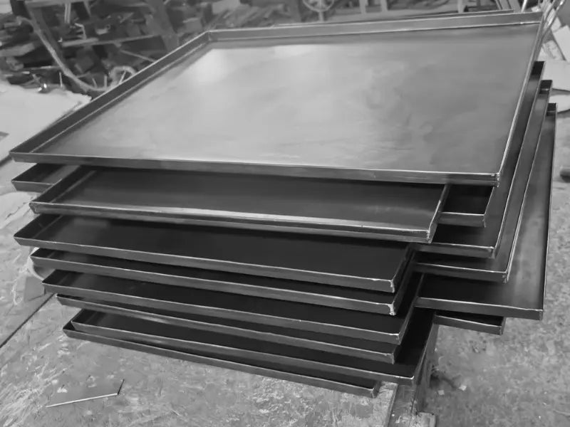 Black steel baking trays stacked during production