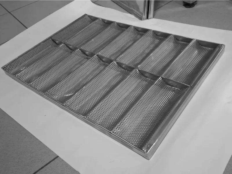 Perforated stainless steel baguette tray with 14 molds in factory angle view