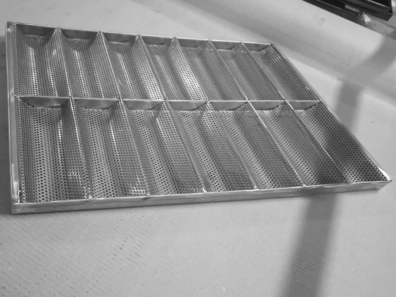 Perforated stainless steel baguette tray with 14 molds during factory production