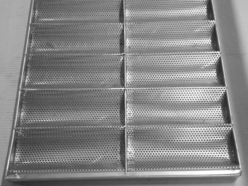 Perforated stainless steel baguette tray with 14 molds in factory workshop