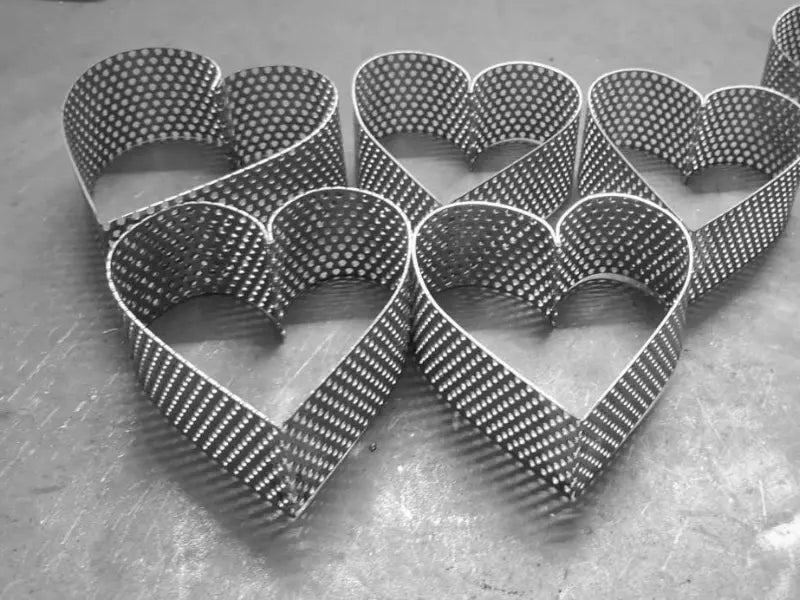 Multiple perforated stainless steel heart pastry rings AISI 304 arranged on work surface