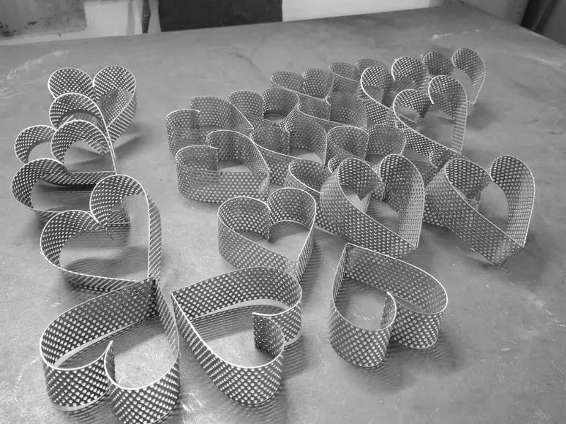 Perforated stainless steel heart pastry rings AISI 304 in production batch on work table