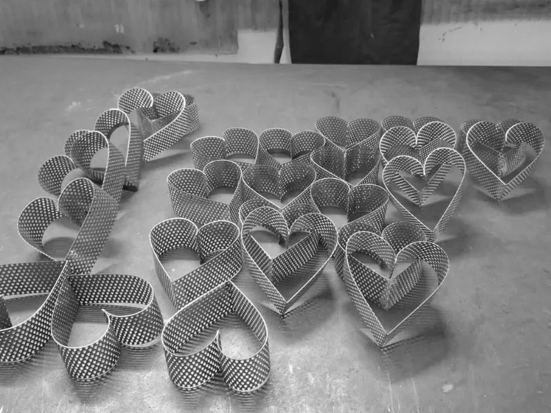 Perforated stainless steel heart pastry rings AISI 304 displayed in workshop setting