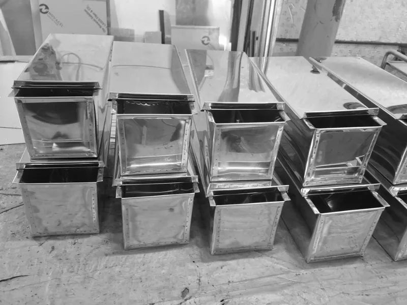 Multiple stainless steel bread loaf pans with lids in workshop