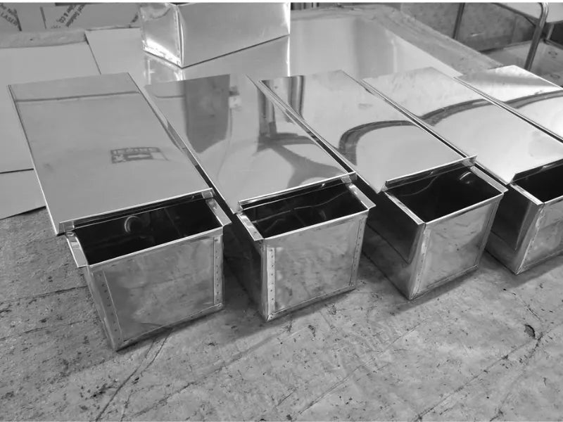 Stainless steel Pullman loaf pans with sliding lids arranged in workshop for bread baking